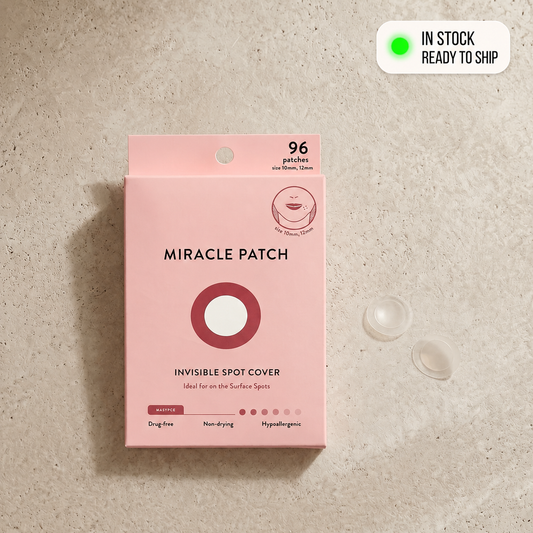 Pink packaging of Miracle Patch on a beige surface with two patches beside it.